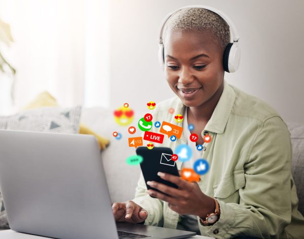 Laptop, social media icon or woman with phone for communication, message or online chat. Headphones, notification emojis or African person streaming music on mobile app on website or network at home.